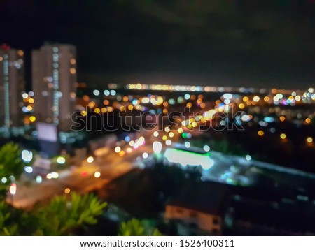 The blurred image of the surrounding high view The road all the way and there is a car traveling around and there are buildings on both sides that are condominiums and housing development at night