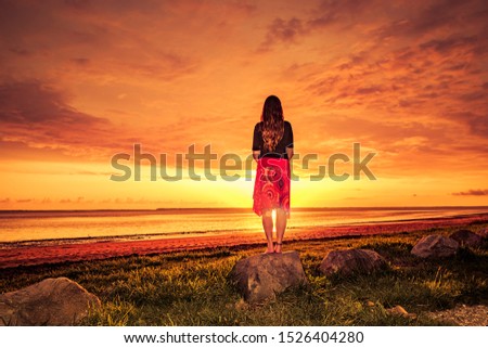 Woman with red skirt enjoys the sunset at the sea