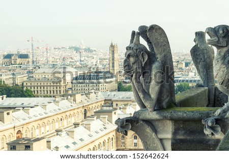 Stone demons gargoyle and chimera with city of Paris on background. View from the tower of the Notre Dame. vintage look picture