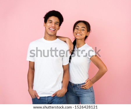 Excited afro couple posing on pink studio background, girl holding hand on guy's shoulder