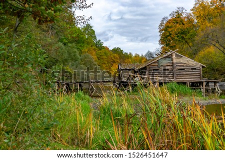 lonely wooden hut on the river in the autumn forest