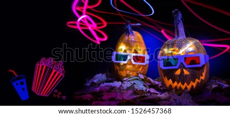 luminous pumpkins on a black background. Halloween autumn holiday. 3D Halloween movie. Pumpkin head Jack in 3D glasses for the film. Bright neon pink and blue light in the darkness of Freezelight.
