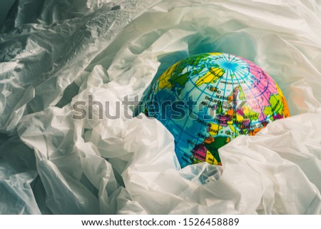 The concept of reducing plastic bags use: Modeled globes are sunk in many white plastic bags. Meaning, plastic bags are about to overflow the world.