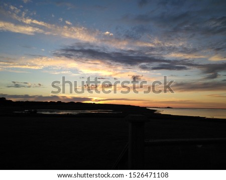 A sunset over the ocean in Prince Edward Island. A gorgeous blue sky with a stunning, and bright glowing horizon accompanied by soft painted clouds