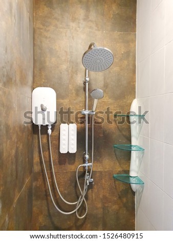 The bathroom comes with a hot shower and a silver shower and shampoo-soap as well as shelves and various accessories. Installed on the brown tile wall Royalty-Free Stock Photo #1526480915