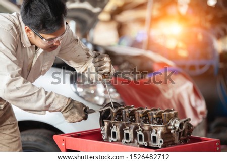 Mechanic with a tool in his hands repairing the motor of the machine. 