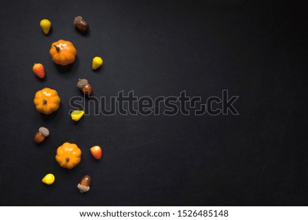 Autumn background of fruits and vegetables: pumpkins and acorns on a black background with copy space. Halloween and harvest concept.