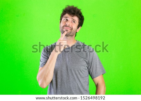 young crazy man thinking confused, disagree expression over green background