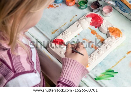 Young artist. Painting photo frames.