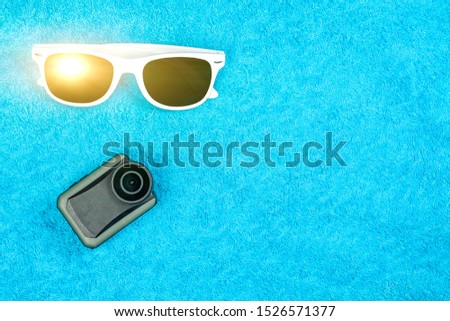 Sunglasses and an action camera lie on a colored towel. Vacation and Travel Concept.