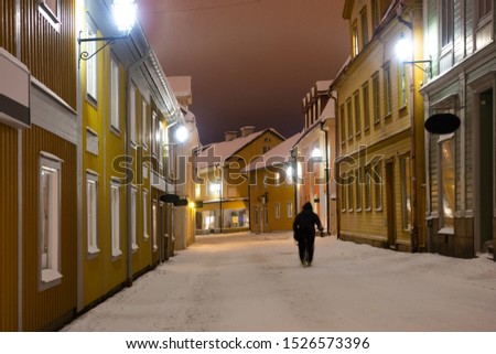 Person in blurred motion walking in small old town street in winter night