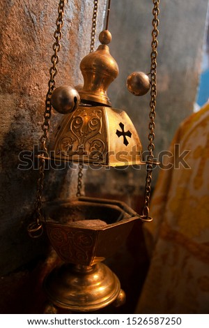 A priest's censer hangs on an old wall in the Orthodox Church. Copper incense with burning coal inside. Service in the concept of the Orthodox Church. Adoration. Royalty-Free Stock Photo #1526587250
