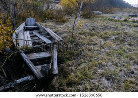 An old broken boat lying on the Bank of a mountain river in the morning autumn weather
