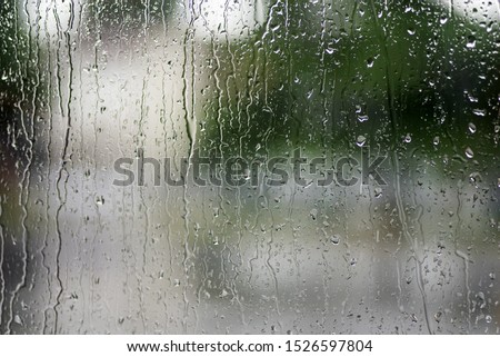 Rain drops on the window with green over background