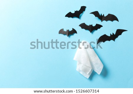 White ghost sheet costume against pastel blue background. Minimal Halloween scary concept.