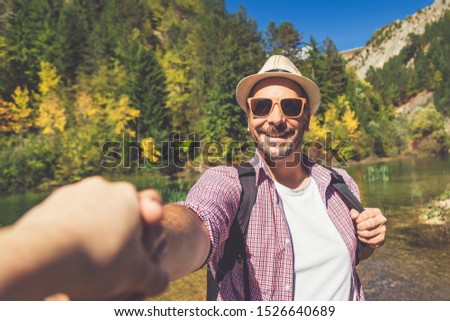 Portrait of fashionable traveler holding woman hand in nature. Travel and love concept.