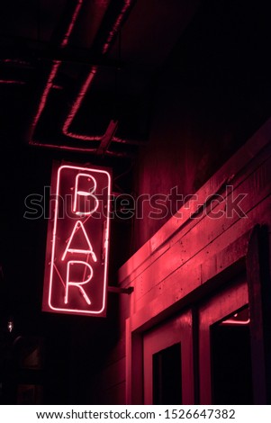 neon BAR sign lights up the doorway of a drinking establishment at night Royalty-Free Stock Photo #1526647382