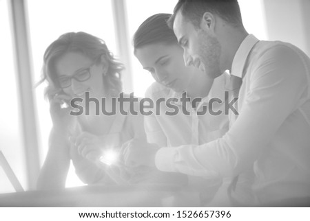 Black and White Photography of business team having a meeting whilst looking at a tablet pc