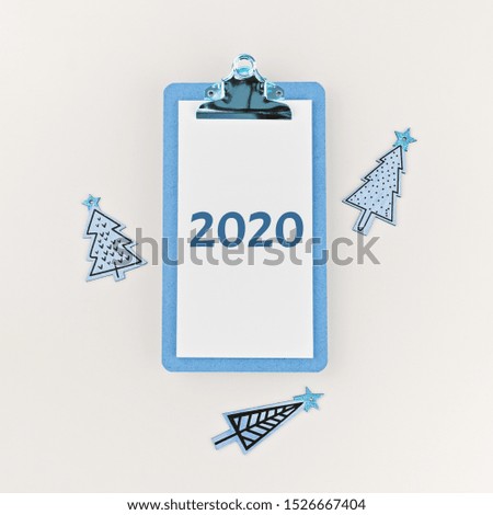 2020 on clipboard and wooden painted funny Christmas trees on white background. Happy New Year and Christmas greeting card mock up, minimalist flat lay style