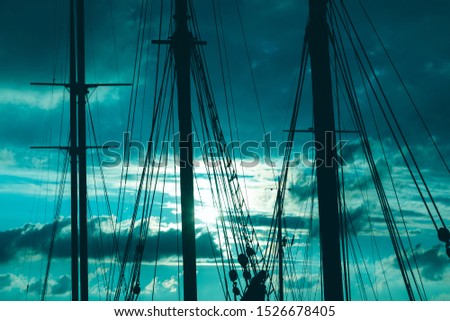 Silhouette of masts and ropes of a wooden old sailing ship against the background of the evening dark blue magical sky