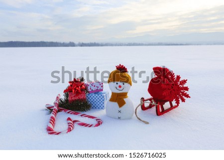 Snowman with red bag with the snowflake on the sledge. Colorful boxes with presents. Striped heart shaped candies. Christmas design. Happy new year 2020.