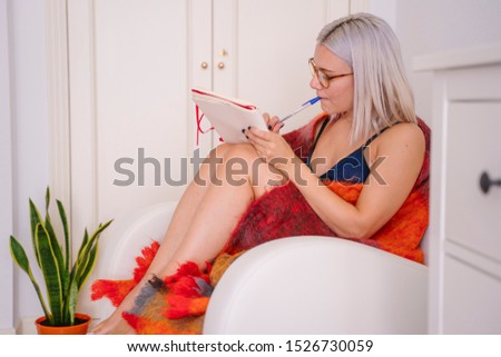 Young journalist writing on her diary at home. Woman taking notes of creative new ideas. Leisure indoors lifestyle.  Creativity and feminist concept.