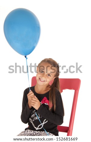 brunette girl holding blue balloon in chair