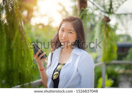 Beautiful young woman enjoying  photographer herself and playing with smartphone. Cute smiling young Caucasian teenage girl taking a selfie outdoors on sunny summer day.