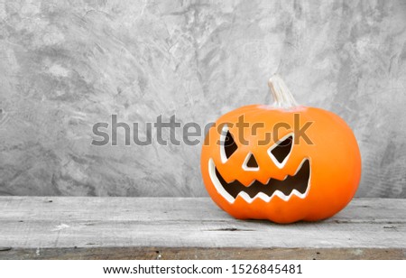 Halloween trick or treat and darkness theme. Pumpkin Jack-o'-lantern on a wooden floor with Background bare cement gray surface and copy space background.