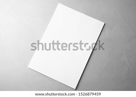 Blank paper sheet on light grey stone background, top view. Mock up for design