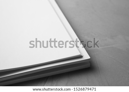 Blank paper sheets on light grey stone background, closeup. Mock up for design