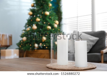Beautiful decorated Christmas tree in living room, focus on burning candles