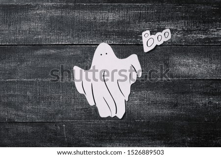 White ghost costume on dark black wooden background. Minimalistic Halloween concept. craft paper ghosts