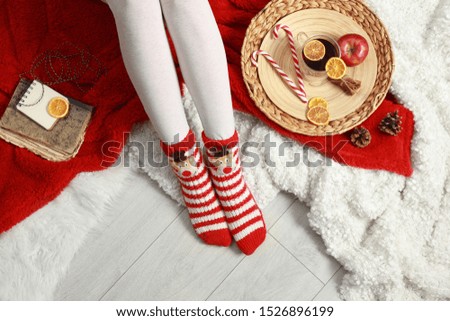 Woman and cup of hot winter drink on floor at home, top view
