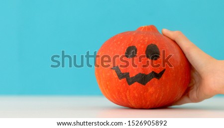Little orange pumpkin dancing on blue background. Halloween holiday hand moves jack pumpkin