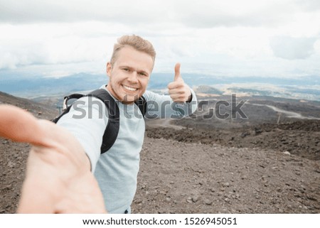 Tourist takes selfie on top of volcano Mount Etna, Sicily Italy. Mountain travel concept.