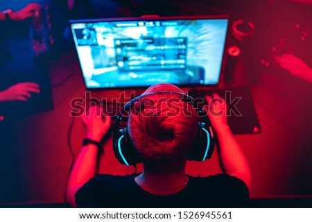Professional cyber gamer studio room with personal computer armchair, keyboard for stream in neon color blur background. Soft focus. Royalty-Free Stock Photo #1526945561
