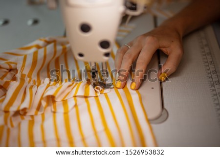 seamstresss tailor sewing a pattern on a shirt at night time working long hours