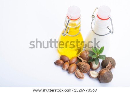 Skin and hair care product, creme or shampoo made from natural argan or macadamia oil in bottle and argan and macadamia  nuts isolated on white background copy space