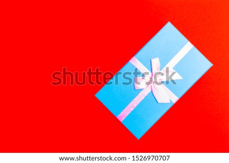 blue gift box with pink ribbon on a red background. view from above