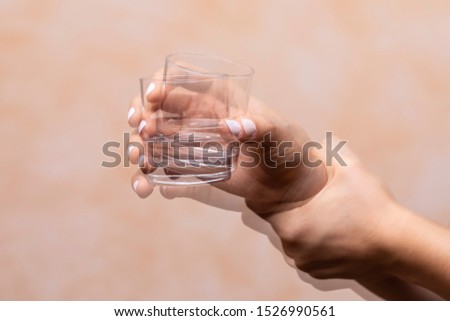 Closeup view on the shaking hand of a person holding drinking glass suffering from Parkinson's disease Royalty-Free Stock Photo #1526990561