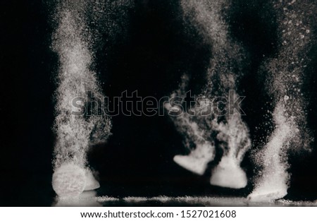 Few tablets dissolving in water with bubbles on black background