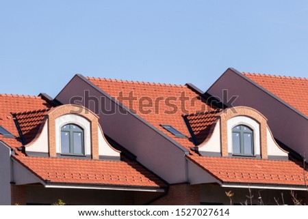 Windows of the attic floor on a bright tiled roof, architectural elements and modern building materials