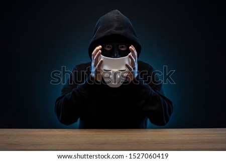 Masked man in hoodie. Dark background. Royalty-Free Stock Photo #1527060419