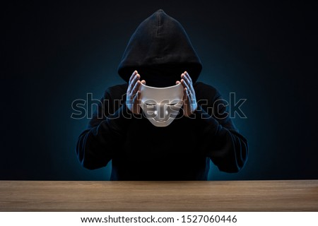 Masked man in hoodie. Dark background. Royalty-Free Stock Photo #1527060446
