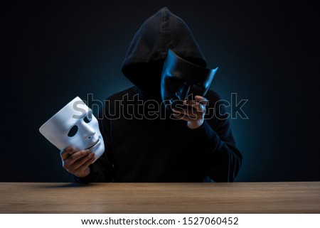Masked man in hoodie. Dark background. Royalty-Free Stock Photo #1527060452