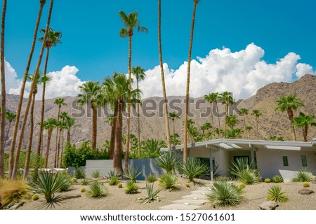 Sunny day at Palm Springs with mountains and palm trees. Beautiful view of hills. Iconic architecture. California style.