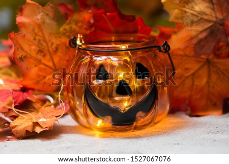 glass lantern pumpkin on a background of leaves