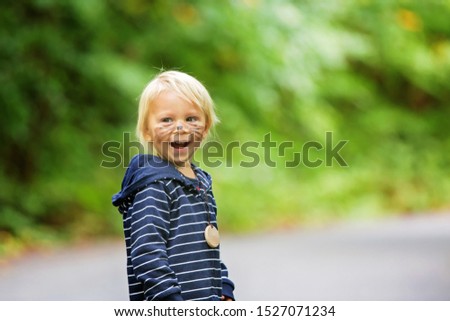 Adorable blond toddler child with bear mask and painted face, smiling