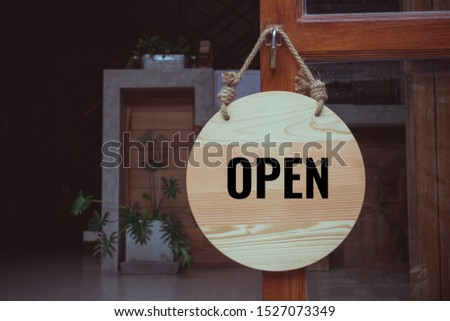 Open sign wooden board bouquet hanging on door at front of cafe or rent house with wood background. Business service